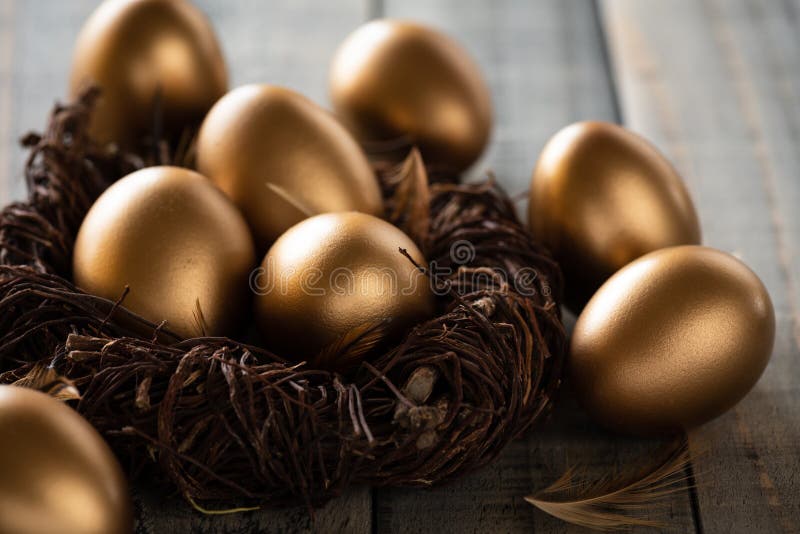 Happy easter! golden of Easter eggs in nest and Feather on wooden background