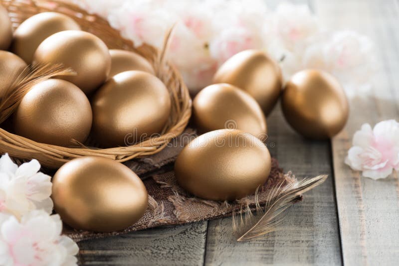 Happy easter! golden of Easter eggs in nest with pink flower and Feather on wooden background