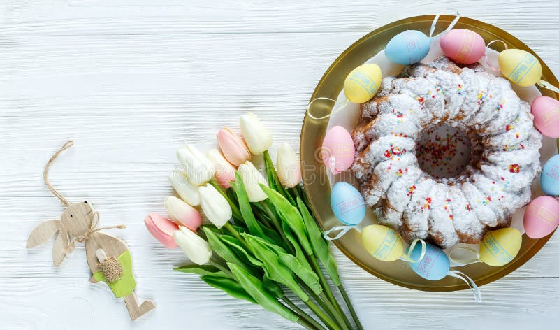 Happy Easter! Golden tray with plate with cake and hand painted colorful eggs, tulips on white wooden table. Close up. Decoration royalty free stock images Happy Easter! Golden tray with plate with cake and hand painted colorful eggs, tulips on white wooden table. Close up. Decoration royalty free stock images