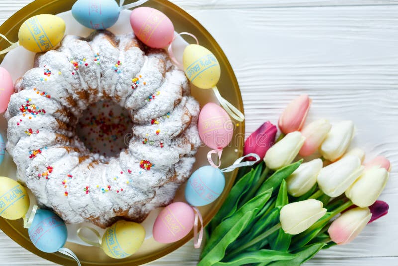 Happy Easter! Golden tray with plate with cake and hand painted colorful eggs, tulips on white wooden table. Close up. Decoration royalty free stock photography Happy Easter! Golden tray with plate with cake and hand painted colorful eggs, tulips on white wooden table. Close up. Decoration royalty free stock photography
