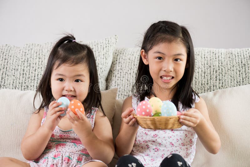 Happy easter! Two cute little children sitting on sofa with Easter eggs in the nest or basket stock image Happy easter! Two cute little children sitting on sofa with Easter eggs in the nest or basket stock image