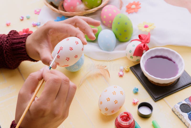 Happy easter! A woman hand painting Easter eggs.