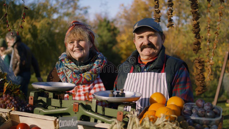 Šťastný starší z zemědělci stojící nejblíže čerstvý a zelenina, kouká na,.