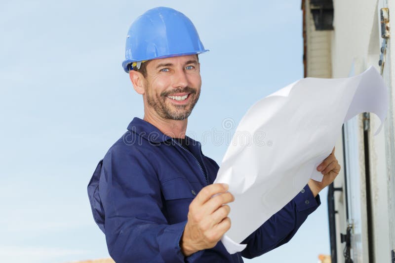 Happy engineer holds paper and smiles stock photo