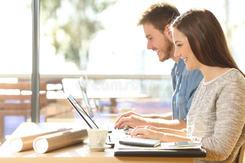Happy entrepreneurs typing on laptops work in a coffee shop stock images Happy entrepreneurs typing on laptops work in a coffee shop stock images