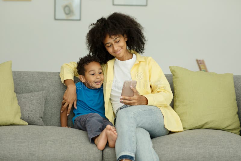 Happy Excited Black Mom And Little Son With Smartphone Celebrate Success By Playing Video Games 