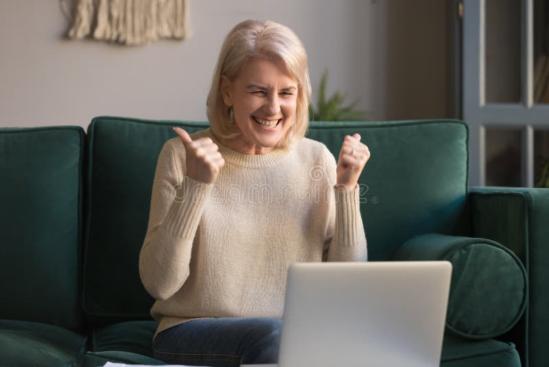 Happy excited grey haired woman celebrating online win, using laptop royalty free stock images Happy excited grey haired woman celebrating online win, using laptop royalty free stock images