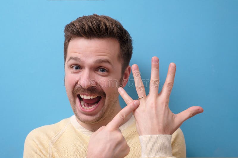 Happy excited man with mustache pointing to wedding ring on his finger