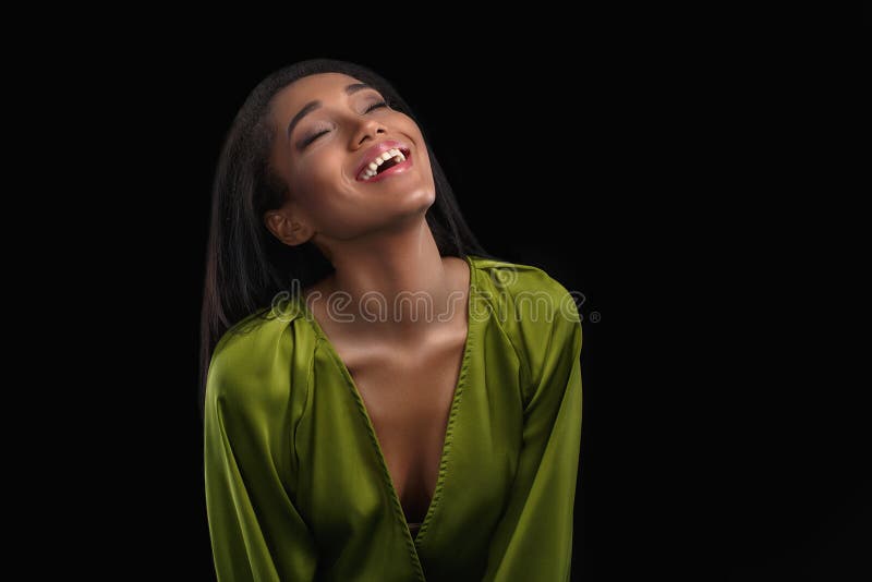 Happy excited young african american woman in green bathrobe laughing over black background