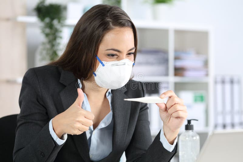 Happy executive checks thermometer in covid-19 quarantine at office stock photo Happy executive checks thermometer in covid-19 quarantine at office stock photo