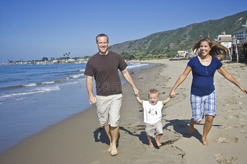 Mladé, krásné rodinné procházky ruku v ruce spolu na pláži.