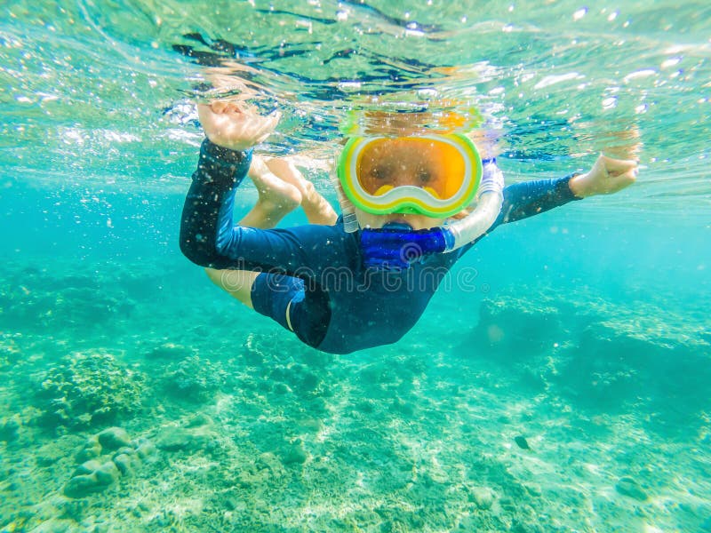 Happy family - active kid in snorkeling mask dive underwater, see tropical fish in coral reef sea pool. Travel adventure