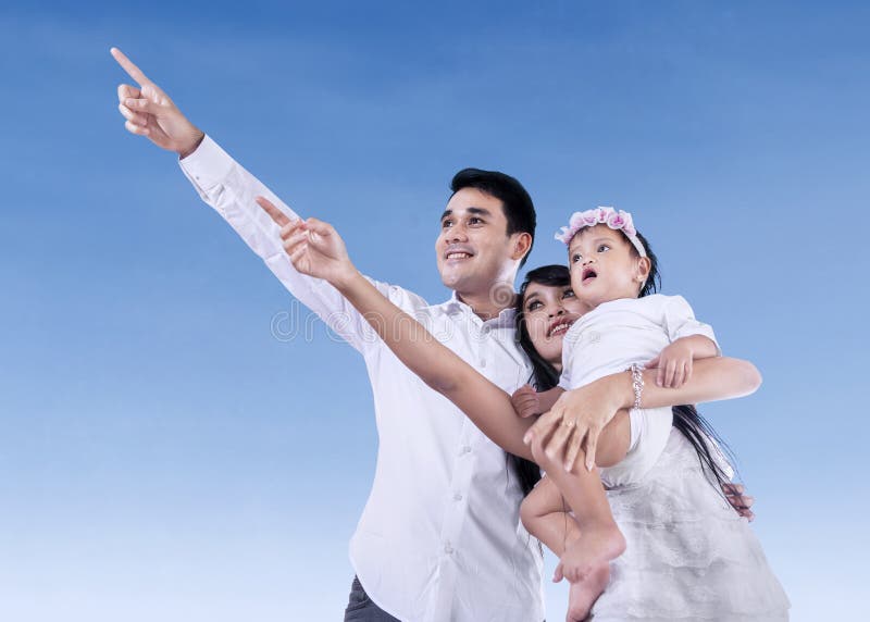 Happy family pointing at blue sky outdoors. Happy family pointing at blue sky outdoors