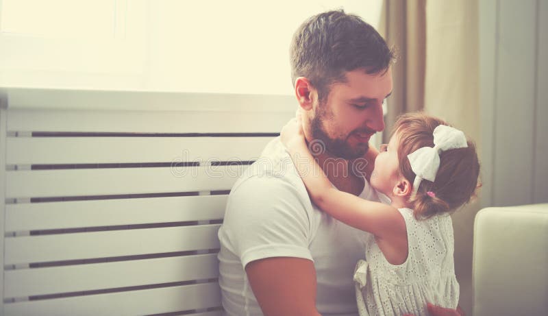 Famiglia felice bambino bambina tra le braccia di suo padre alla finestra di casa.