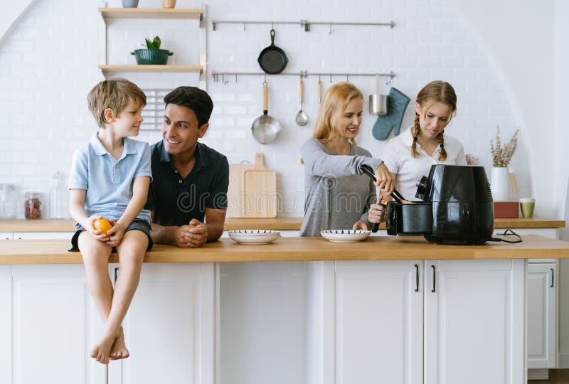 Happy family cooking morning breakfast together in kitchen at home. Mother and daughter cooking toast bread by Air Fryer machine. To father and son. Home royalty free stock photo
