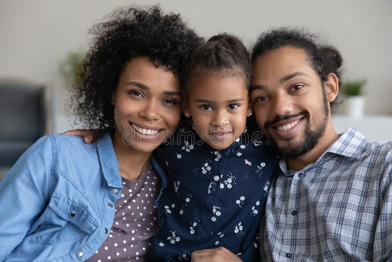 Happy family couple holding adorable little daughter child in arms