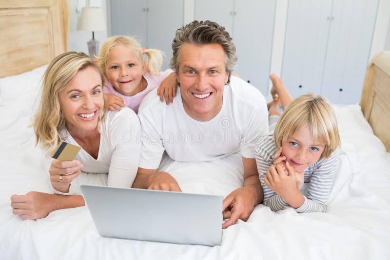 Happy family doing online shopping on laptop in the bed room stock images Happy family doing online shopping on laptop in the bed room stock images