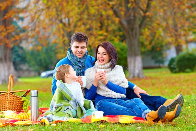 Happy family drinking warm tea on autumn picnic