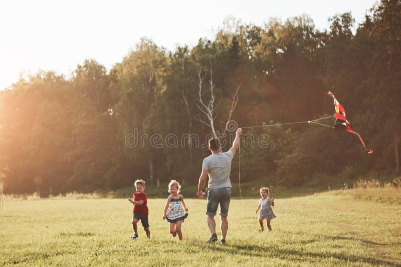 Happy family father and childs run with a kite on meadow royalty free stock image Happy family father and childs run with a kite on meadow royalty free stock image