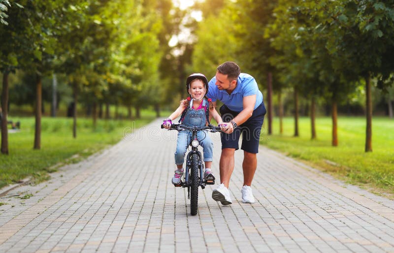 Happy family father teaches child daughter to ride a bike in the Park royalty free stock photo Happy family father teaches child daughter to ride a bike in the Park royalty free stock photo