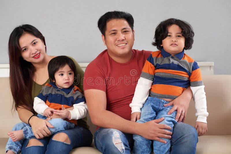 Happy Filipino family of four sitting on sofa. Happy Filipino family of four sitting on sofa