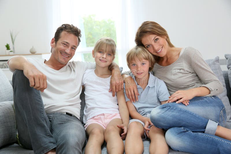 Happy family of four relaxing on sofa stock image