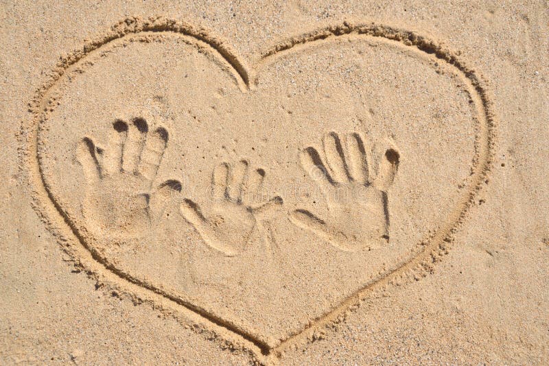 Drawing heart with family hand print on sand.Concept of family traveling, vacation, happiness family. Drawing heart with family hand print on sand.Concept of family traveling, vacation, happiness family.