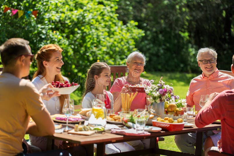 Happy family having dinner or summer garden party. Leisure, holidays and people concept - happy family having festive dinner or summer garden party royalty free stock image