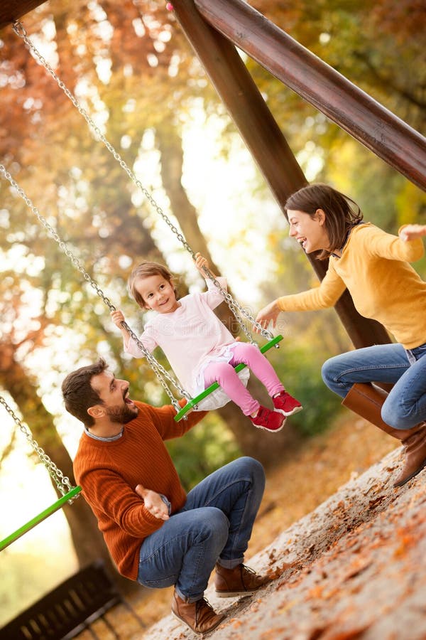 Happy family having fun on a swing ride at a garden a autumn day