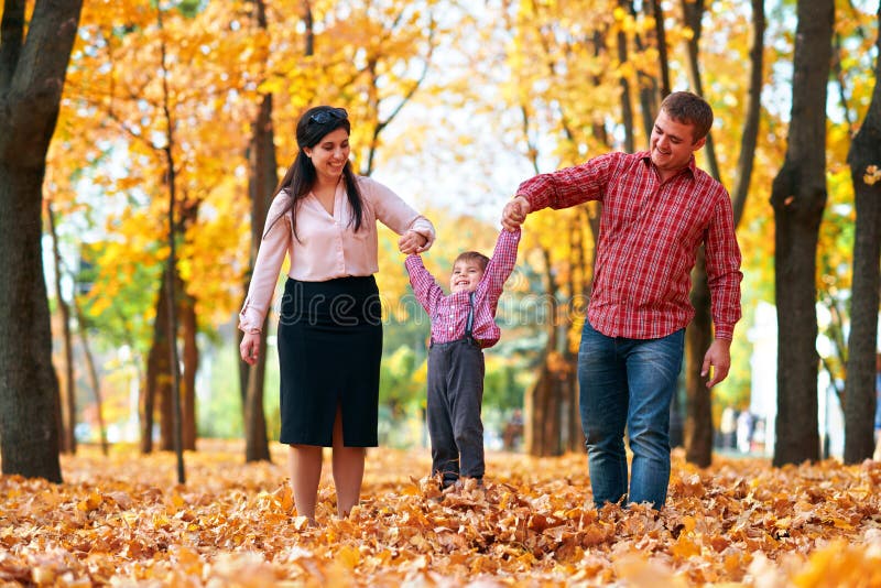 Happy family having holiday in autumn city park. Children and parents posing, smiling, playing and having fun. Bright yellow trees stock photography Happy family having holiday in autumn city park. Children and parents posing, smiling, playing and having fun. Bright yellow trees stock photography