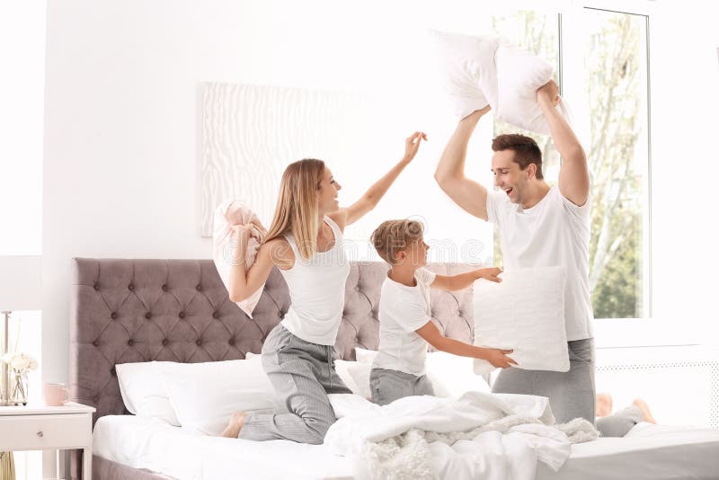 Happy family having pillow fight on bed