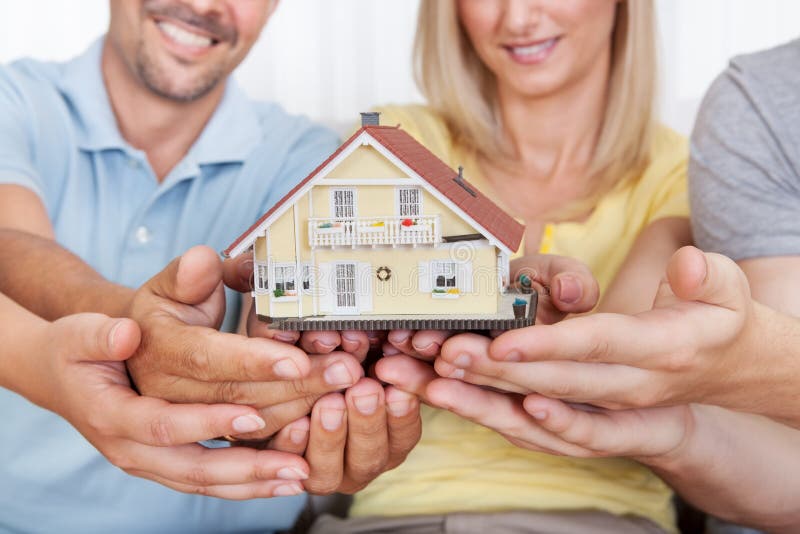 Happy family holding a model house. Happy parents with their teenage son and daughter holding a model house conceptual of setting a goal for home ownership stock images Happy family holding a model house. Happy parents with their teenage son and daughter holding a model house conceptual of setting a goal for home ownership stock images