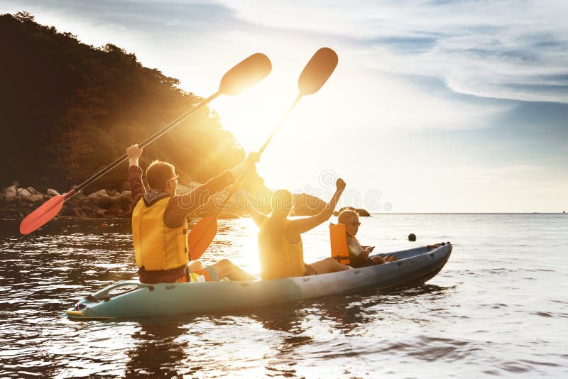 Happy family kayaking sunset sea. Happy family of father mother and son kayaking and having fun at sunset sea bay royalty free stock photo