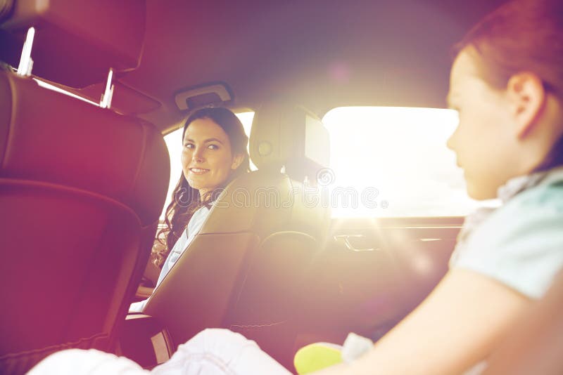 Family, transport, road trip and people concept - happy women with little daughter driving in car. Family, transport, road trip and people concept - happy women with little daughter driving in car