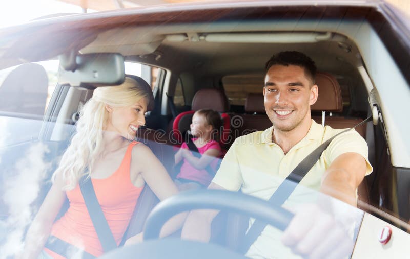 Family, transport, safety, road trip and people concept - happy men and women with little child driving in car. Family, transport, safety, road trip and people concept - happy men and women with little child driving in car