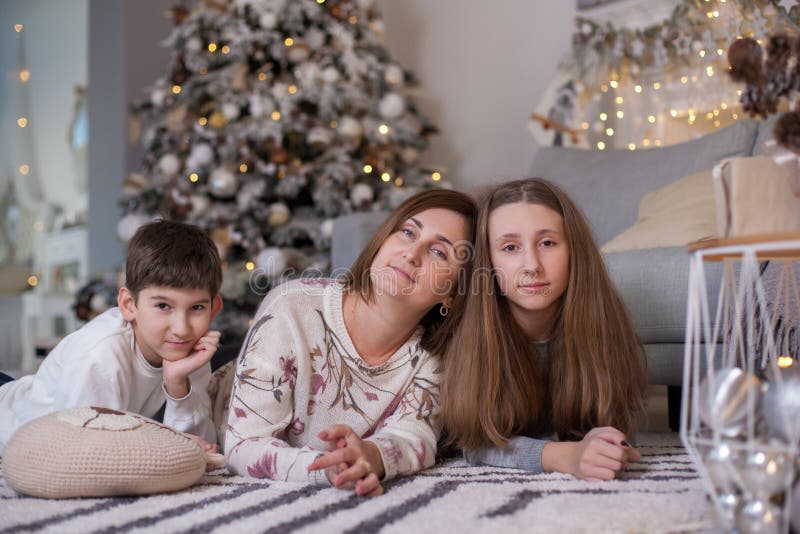 Mother and children lying on floor near christmas tree royalty free stock photo