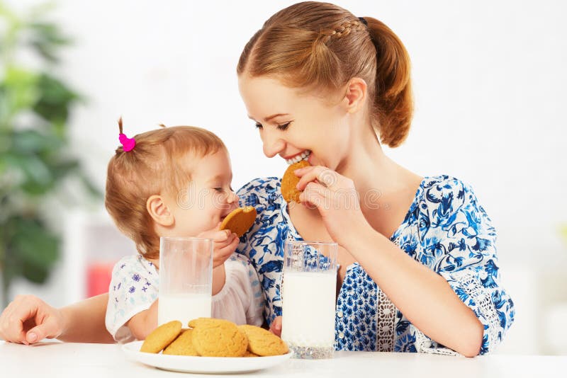 Happy family mother and baby daughter girl at breakfast: biscuit