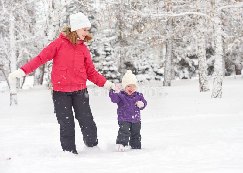 Happy family mother and baby girl daughter run, walk and playing in winter snow stock photo Happy family mother and baby girl daughter run, walk and playing in winter snow stock photo