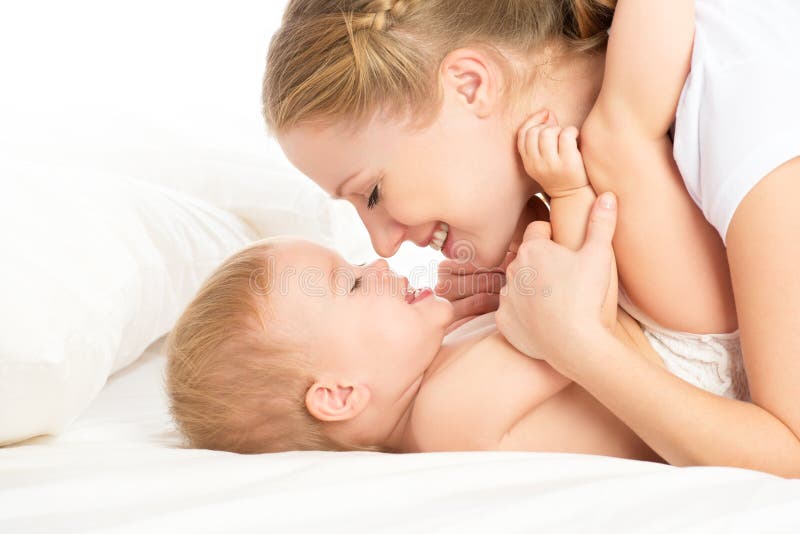 Famiglia felice la madre e il bambino a divertirsi a giocare, baciare ridere sul letto.