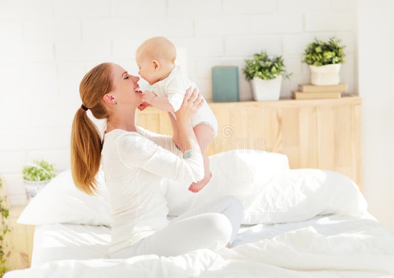 Happy family mother with baby playing and hug in bed royalty free stock image