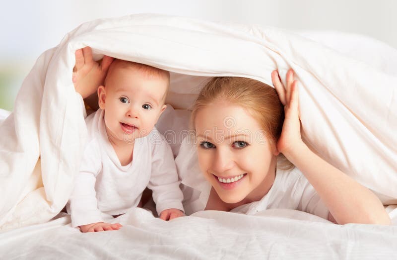 Happy family. Mother and baby playing under blanket