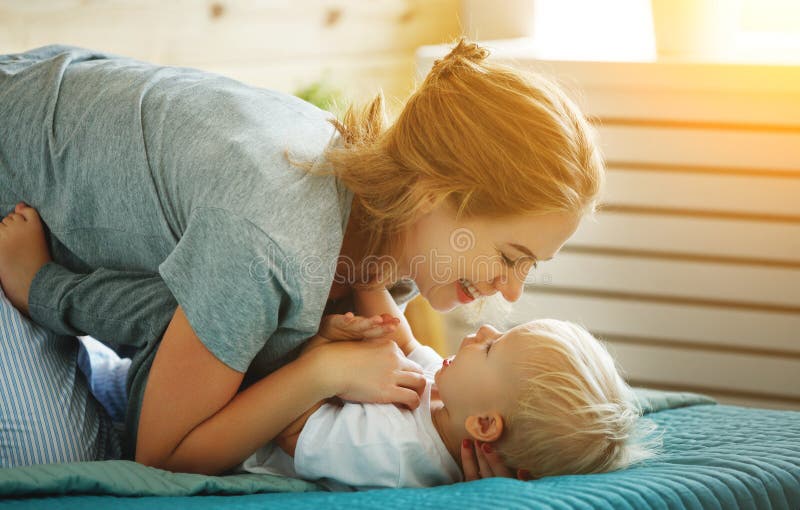 Happy Family Mother And Baby Son Toddler Laughing In Bed Stock Photo