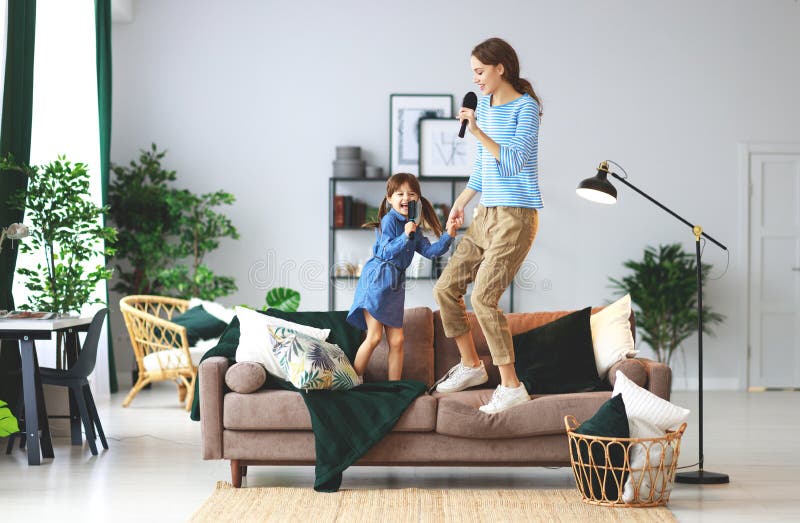 Happy family mother and child daughter play at home and sing with combs