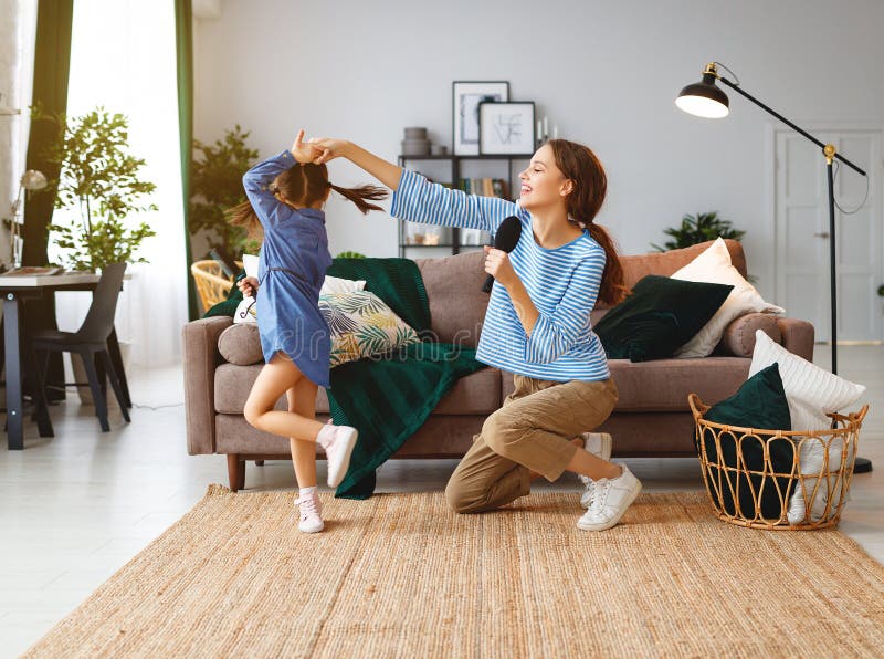 Happy family mother and child daughter play at home and sing with combs