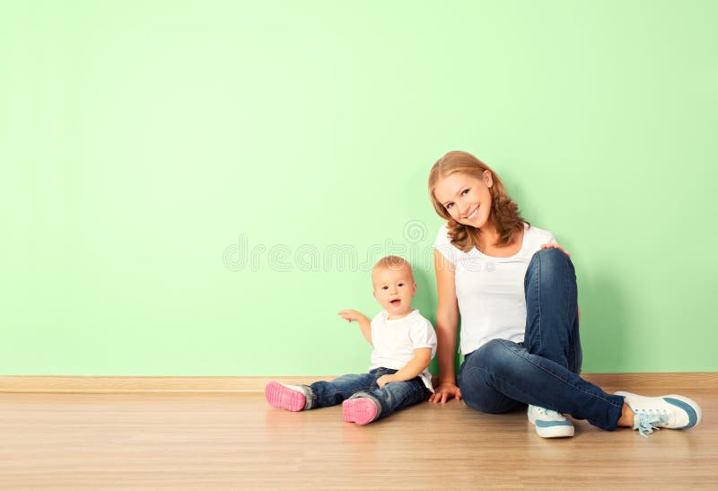Famiglia felice della madre e del bambino è un bambino seduto sul pavimento in una casa vuota parete della stanza.