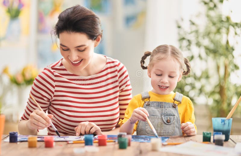 Happy family. Mother and daughter painting together. Adult woman helping to child girl. Happy family. Mother and daughter painting together. Adult woman helping to child girl