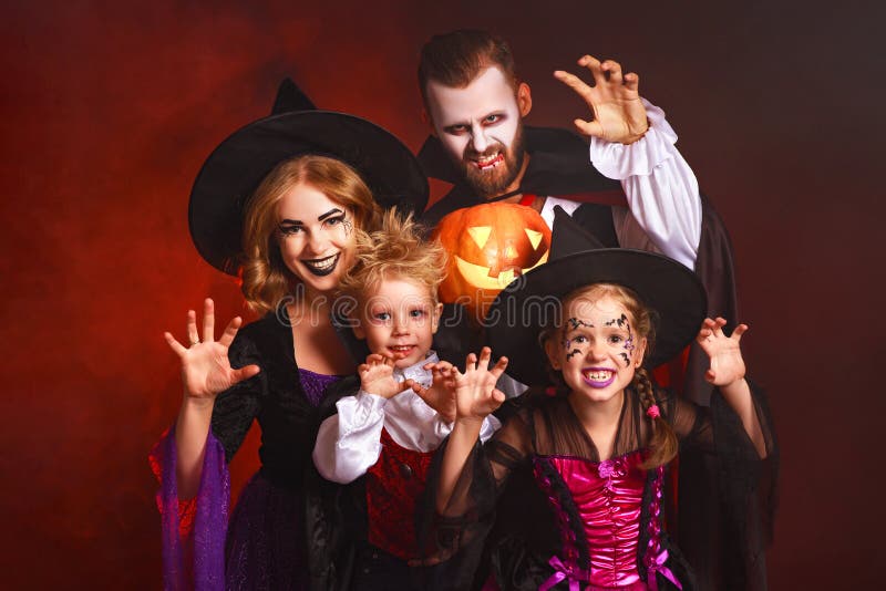 Happy family mother father and children in costumes and makeup on Halloween on dark red background royalty free stock photo Happy family mother father and children in costumes and makeup on Halloween on dark red background royalty free stock photo