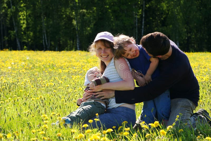 Happy family of mother, father and two sons in dandelion field