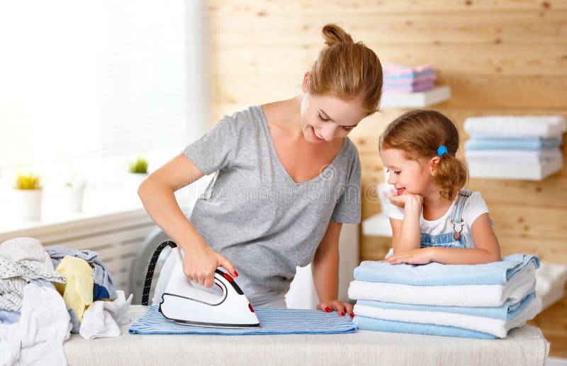Happy family mother housewife and child daughter ironing clothes