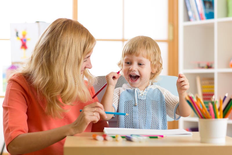 Happy family mother and kid son together paint. Woman helps child boy.